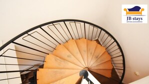A spiral staircase with a wooden handrail and black metal balusters.