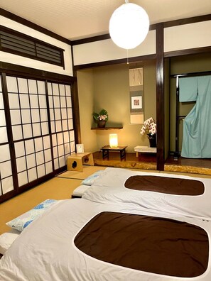 A traditional Japanese room with tatami flooring, two tatami mats, a shoji screen, a small table with a lamp, a potted plant, and a mirror with a curtain. - Japanese harmony  comfort at Mitsuba House - Rental of a whole building / Annaka Gunma (Annaka)