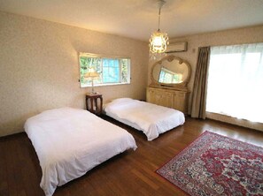 Two single beds are aligned against the wall, with a large mirror above and a chandelier hanging from the ceiling.