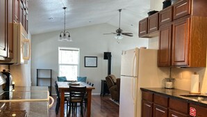 A kitchen with wooden cabinets, a refrigerator, and a dining area with a table and chairs. - Cozy Cabin (Red River)