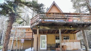 A two-story lodge with a wooden deck and a covered front porch. - Cozy Cabin (Red River)