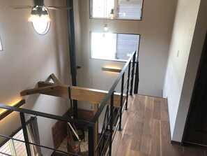 A modern interior with a wooden staircase, metal railings, and a view of the outside through a window.