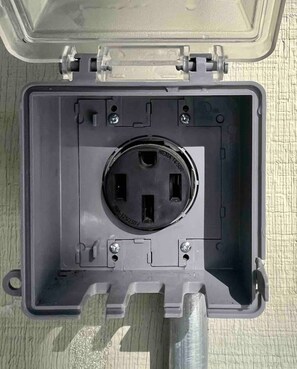 A gray electrical box with a circular socket and two screw holes on the side.
