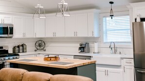 A modern kitchen with white cabinets, a stainless steel refrigerator, and pendant lighting.