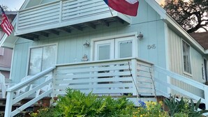 Et lyseblåt hus med balkon, flag og nummer 1045 på siden.
