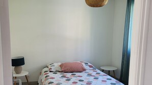 A bedroom with a bed, bedside table, lamp, and a hanging light fixture. - T2 near historic center (Manosque)