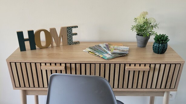 A wooden desk with a chair, a 'HOME' sign, magazines, and two potted plants. - T2 near historic center (Manosque)