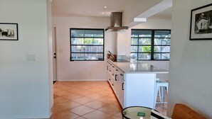 A modern kitchen with a large island, white cabinetry, and a view through the windows. - Boca Raton Home with private heated pool, close to FAU, Beach & Mizner! (Boca Raton)