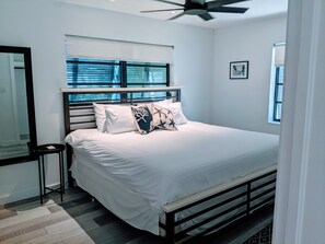 A neatly arranged bedroom with a bed, bedside table, and a ceiling fan. - Boca Raton Home with private heated pool, close to FAU, Beach & Mizner! (Boca Raton)