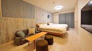 A modern hotel room with a large bed, a sofa, a small table, and ottomans. - Deluxe Room 204 - 204 / Osaka Ōsaka (Osaka)