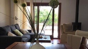 Een moderne woonkamer met een donkere bank, een beige bank, een houten salontafel en een witte vaas met groene planten.