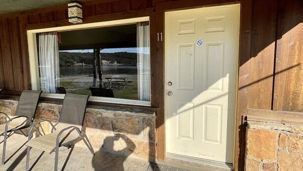Eine Holzhütte mit Steinfassade, eine Tür mit der Nummer 11 und eine Terrasse mit Metallstühlen und einem Tisch.