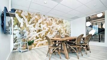 Une salle de conférence dotée d’une grande fresque murale, d’une table en bois et de chaises en osier.