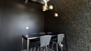 A modern dining area with a dark wall, a patterned wall, and a black table with chairs.