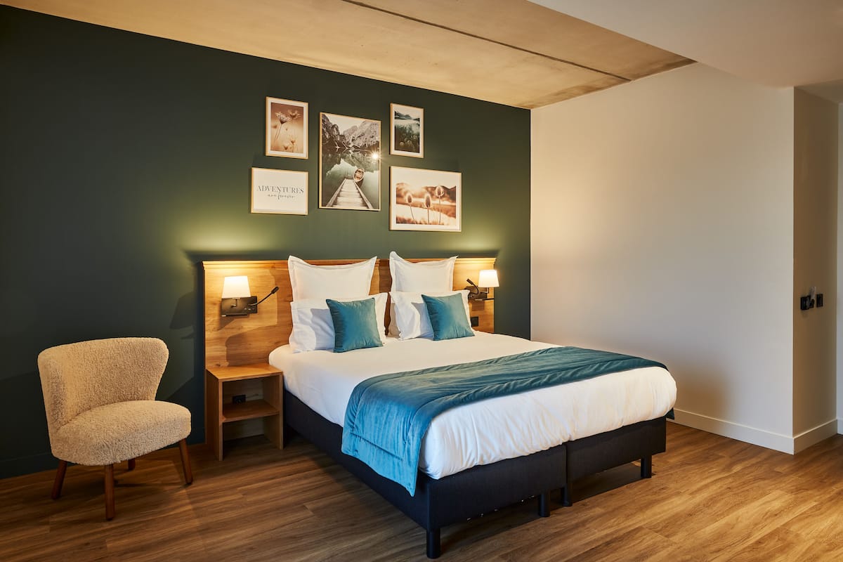 A bedroom with a bed, bedside tables, a chair, and wall-mounted lamps.