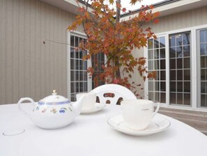 Enjoy a tranquil tea service in a serene outdoor setting with a traditional Japanese-style table and seating for two.