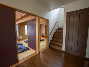 Um quarto em estilo japonês tradicional, com piso de tatame, uma porta deslizante e uma escada de madeira.
