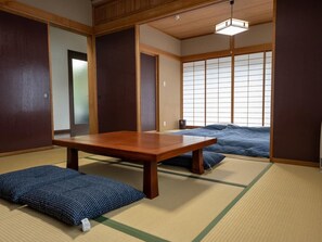 Um quarto japonês tradicional com tatames, uma mesa de madeira baixa e um futon.
