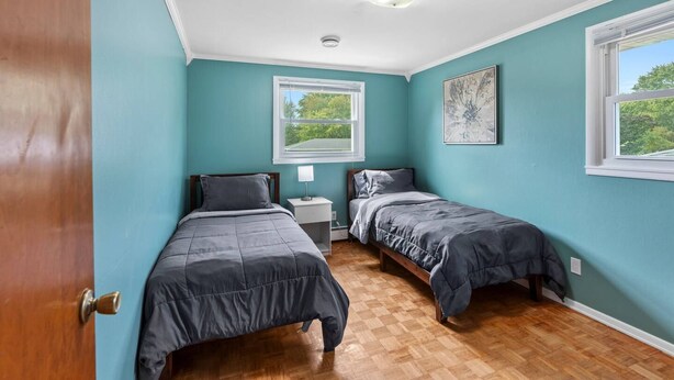 Quarto com duas camas de solteiro, uma mesa de cabeceira, uma janela e um lustre.