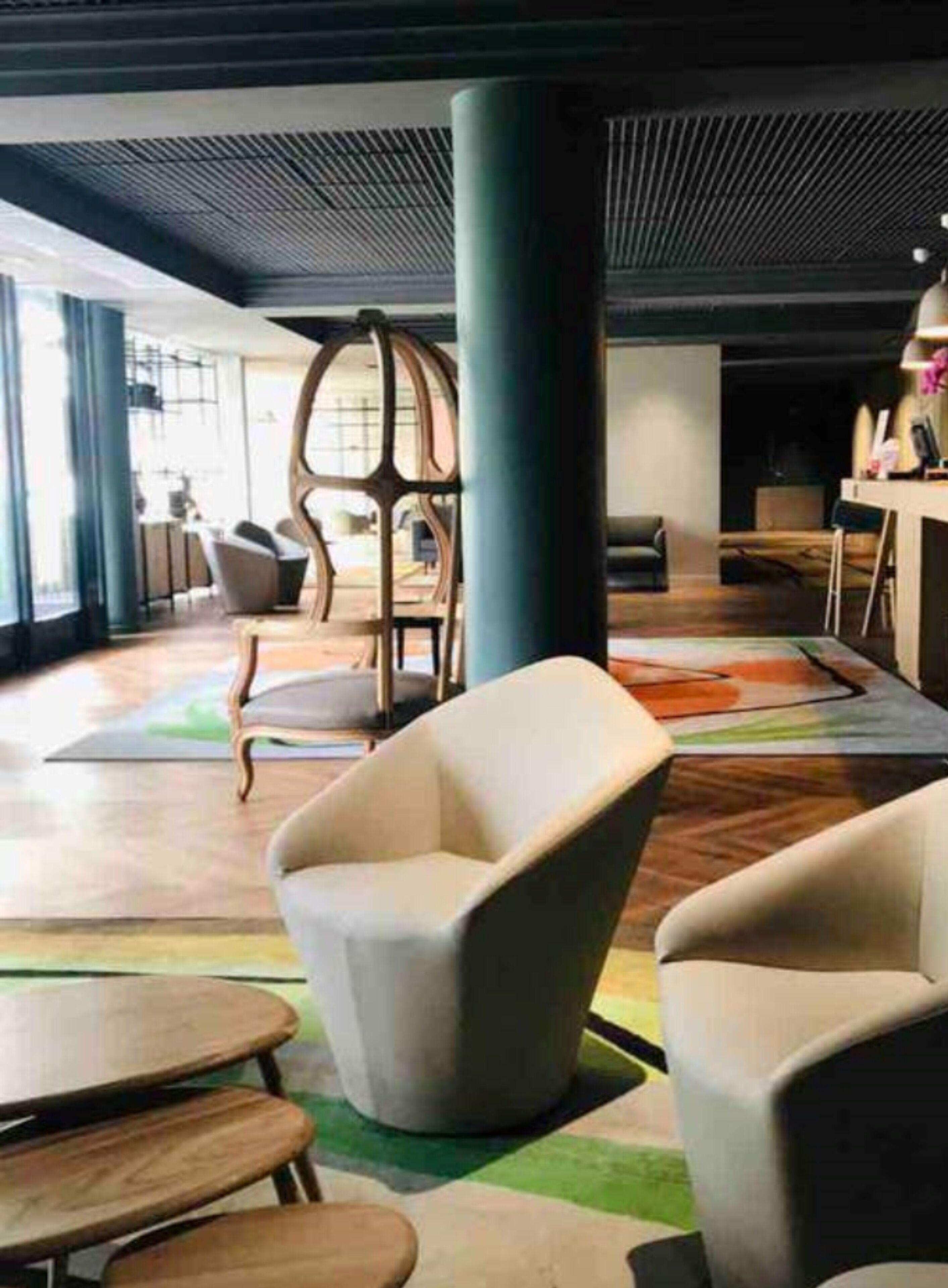 Ein moderner Lounge-Bereich mit bequemen Sitzgelegenheiten, einer großen Säule und einem farbenfrohen Teppich.