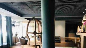 Un área de lounge moderna con asientos cómodos, un pilar grande y una alfombra colorida.