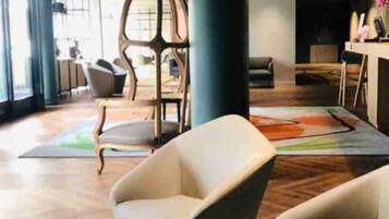 Ein moderner Lounge-Bereich mit bequemen Sitzgelegenheiten, einer großen Säule und einem farbenfrohen Teppich.