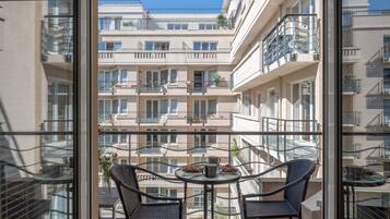 Ein Balkon mit zwei Stühlen und einem Tisch, mit Blick auf ein mehrstöckiges Gebäude mit Balkonen.