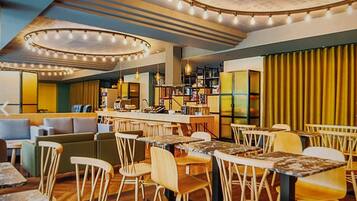 Ein modernes Restaurant mit Barbereich, Holzhockern und einer Mischung aus Sitzgelegenheiten, darunter Sofas und Tische.