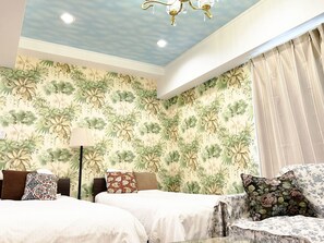 Habitación de hotel con dos camas, una araña y diseño de papel tapiz floral.