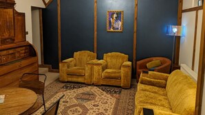 A room with dark blue walls, a wooden cabinet, two armchairs, a sofa, a patterned rug, and a chandelier. - Lovely Stables mew's house in hidden town location (Royal Tunbridge Wells)