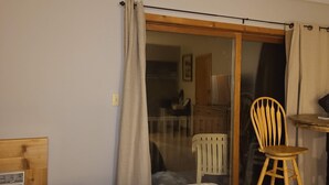 Una habitación con puerta de vidrio corredera, una mesita redonda y una silla, además de un radiador.