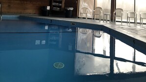 Una piscina interior con vigas de madera, tragaluces y vistas al exterior a través de amplios ventanales.