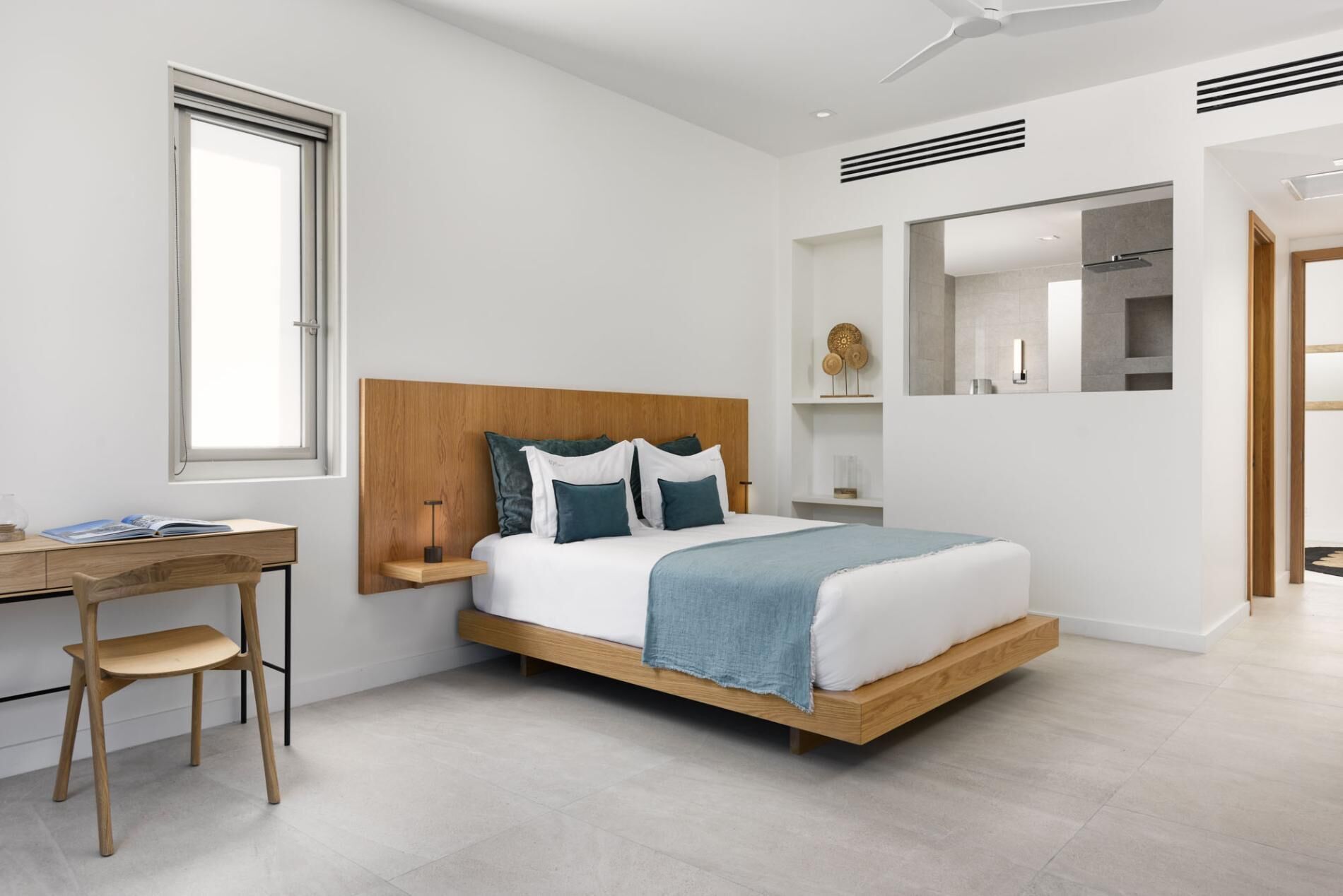 Un dormitorio moderno con estructura de cama de madera, un escritorio con silla y un ventanal grande.