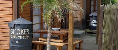 Relax in the outdoor seating area with a table and benches, featuring a smoker nearby.