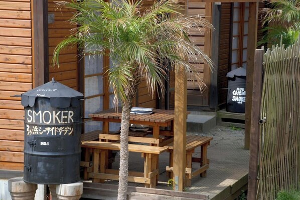 Relax in the outdoor seating area with a table and benches, featuring a smoker nearby.