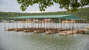 A wooden dock with a covered pavilion over a lake, surrounded by trees and hills. - Lake front Cabin #11 with Porch - Cabin with kitchen, steps from Possum Kingdom Lake (Graham)