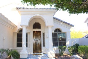 A house with a white exterior, a wooden front door, and two windows on either side of the door.