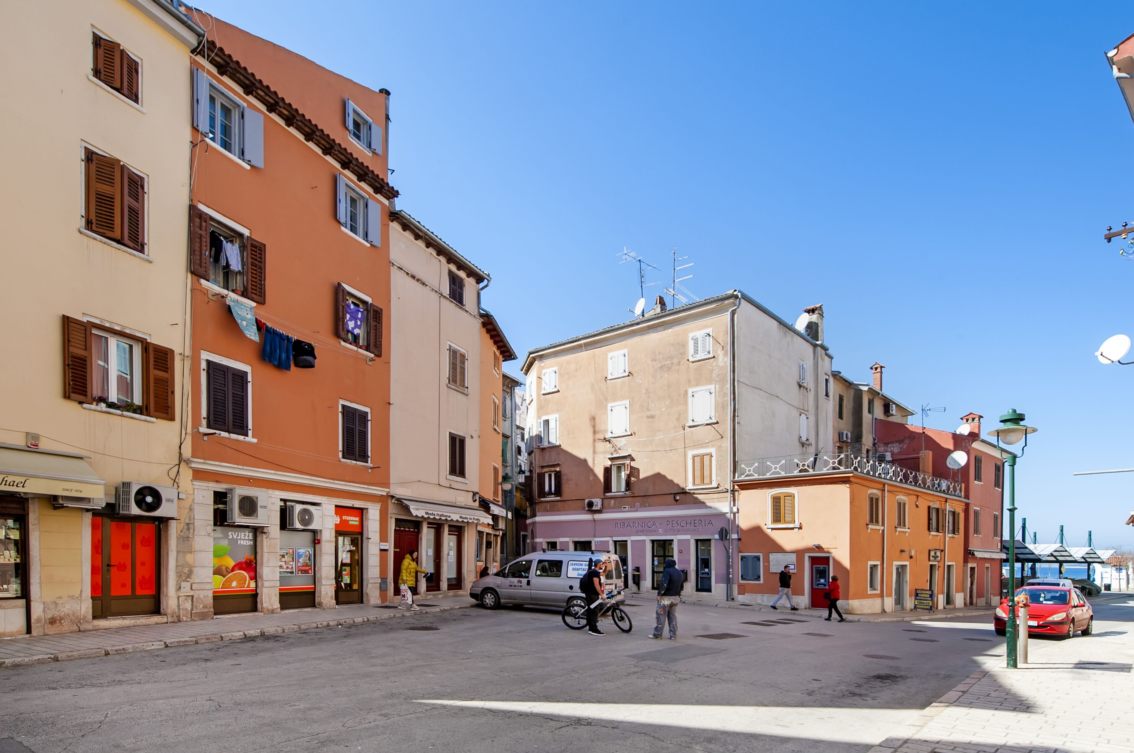 Une rue bordée d’immeubles, avec un fourgon garé et une moto.