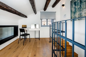 Enjoy a room with a desk, chair, and window offering a view of the outside, plus a staircase or balcony area.