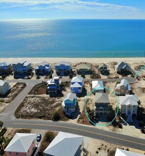 A coastal residential area with houses and a road leading to the beach.