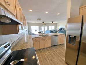 Enjoy cooking in this well-lit kitchen with a large island, dishwasher, stainless steel refrigerator, and black stovetop.