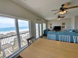 Enjoy ocean views from the large window in this stylish living room, featuring a dining table, sofa, and flat-screen TV.