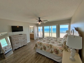 Relax in this serene bedroom with a large bed, ceiling fan, flat-screen TV, and ocean views.