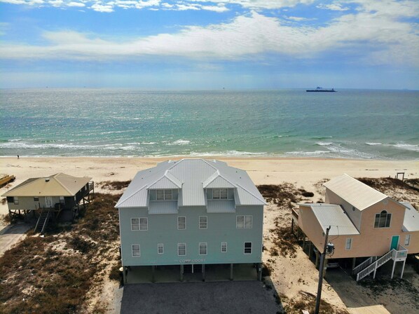 En ejendom ved stranden med et stort hus med skiltet "The Comm Odore" og en mindre bygning ved siden af.