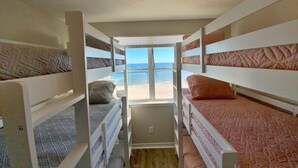 Een slaapkamer met stapelbedden en uitzicht op het strand.