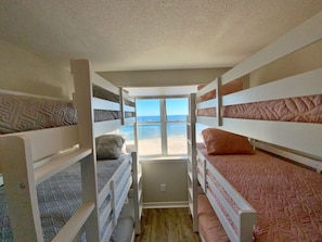 A bunk bed room with a view of the beach.