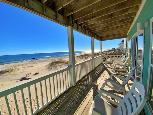 A beachside balcony with a view of the ocean, wooden deck, and beach chairs. - Beachfront and Updated! Pets OK! (Gulf Shores)