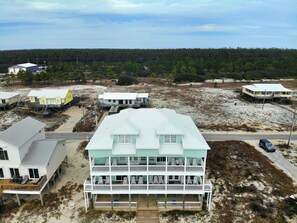 A multi-story beachfront property with a large balcony area, a covered porch, and a sandy beach in the background. - Beachfront and Updated! Pets OK! (Gulf Shores)