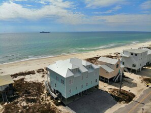 A coastal property with multiple buildings, including a two-story house with a balcony and a smaller attached structure. - Beachfront and Updated! Pets OK! (Gulf Shores)