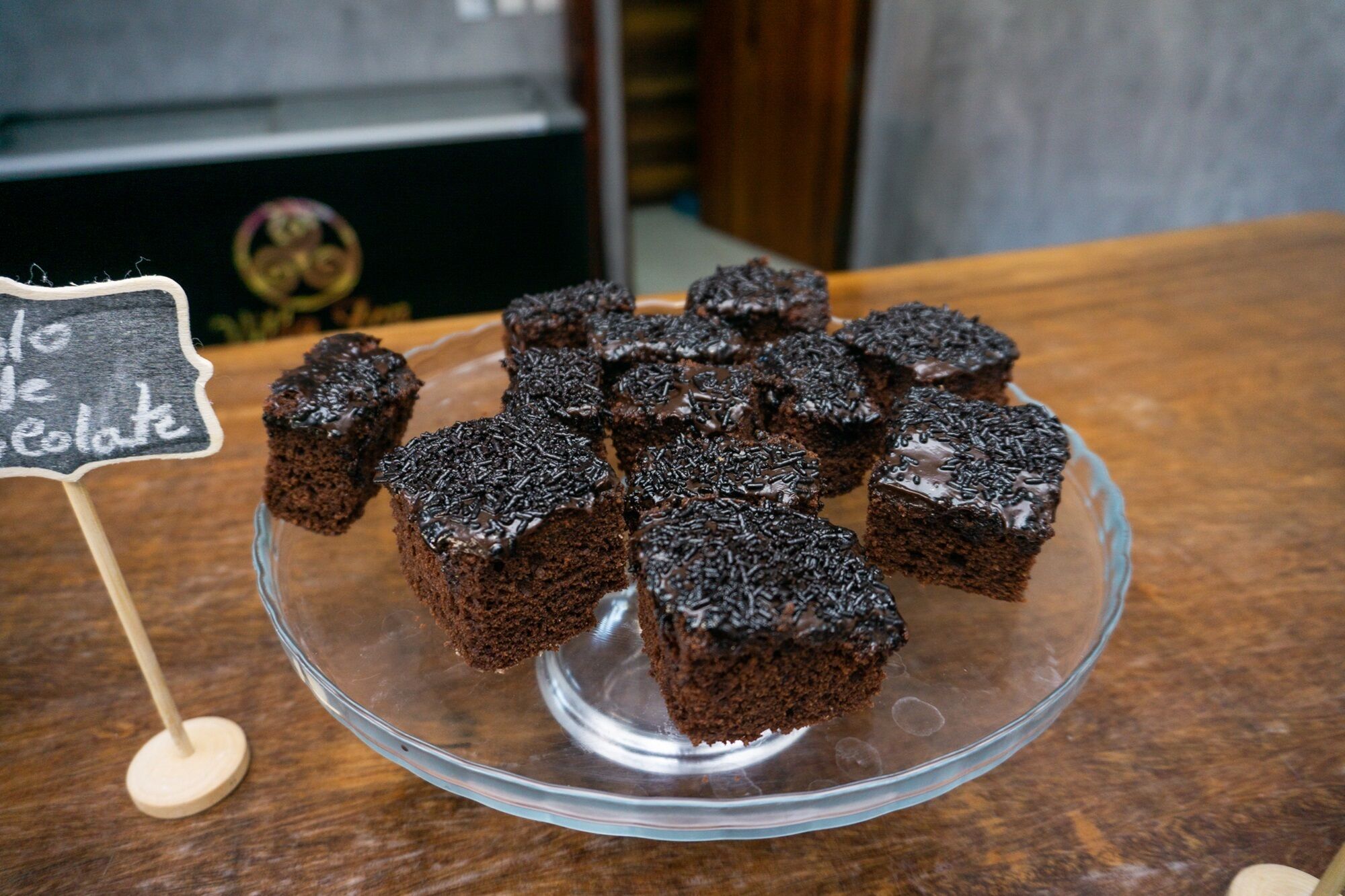 Um suporte de vidro para bolos com brownies de chocolate cobertos com granulado.